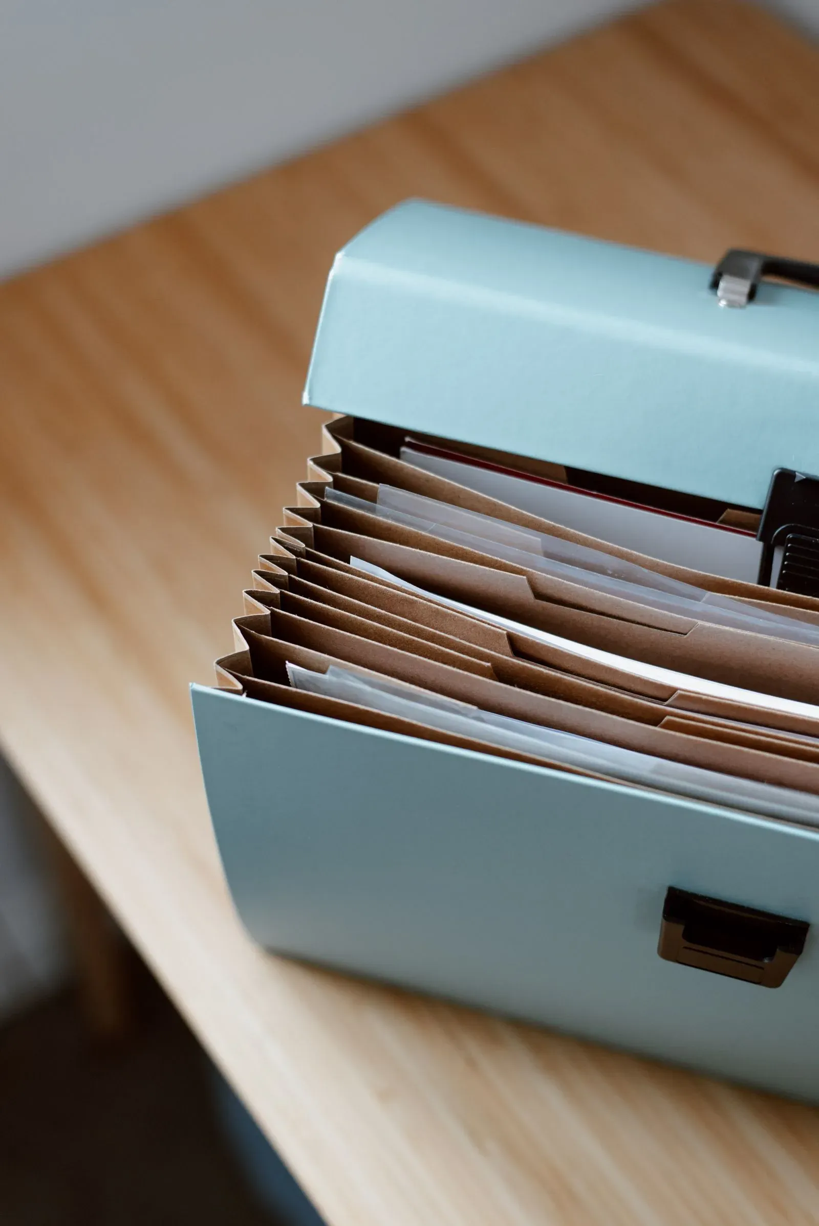 木の机に置かれた水色の書類ケースと、中に立てられた茶色の仕切り