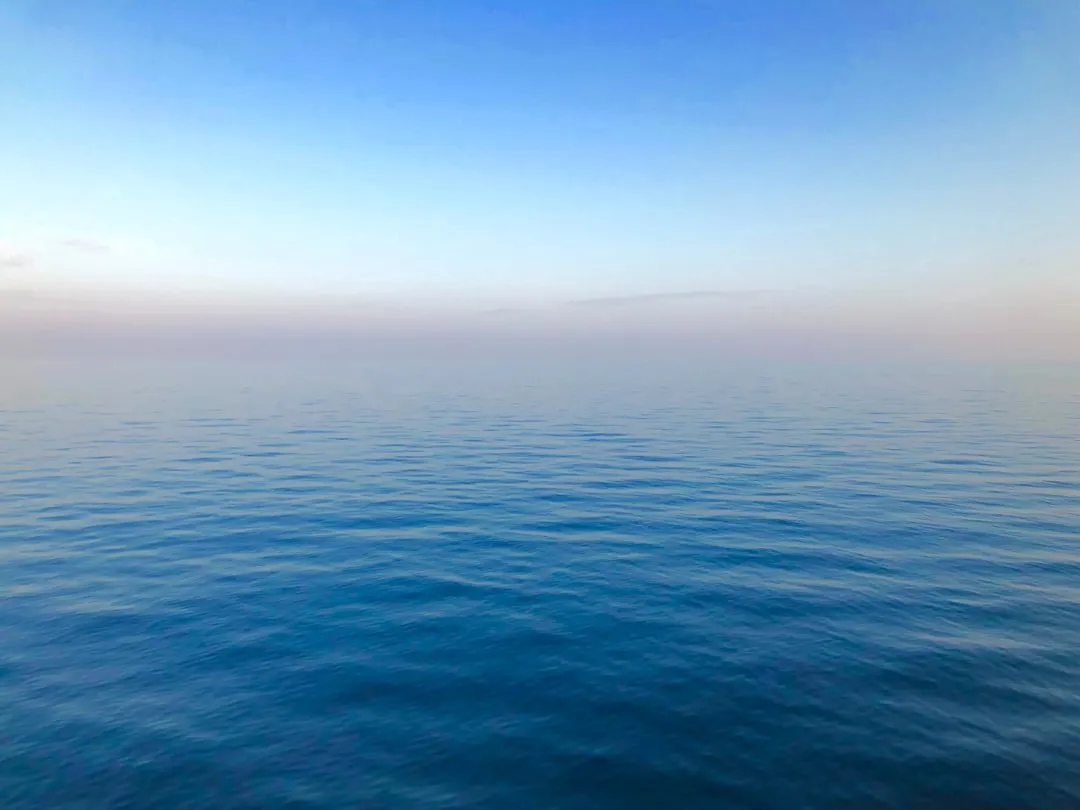 波の穏やかな海面と、水平線までひらけた空