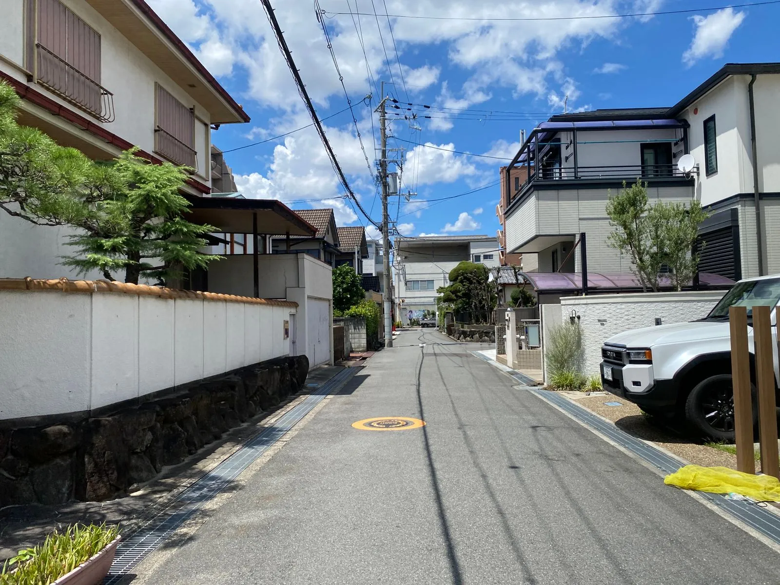 電柱と生け垣が続く日本の住宅街の細い道と、青空