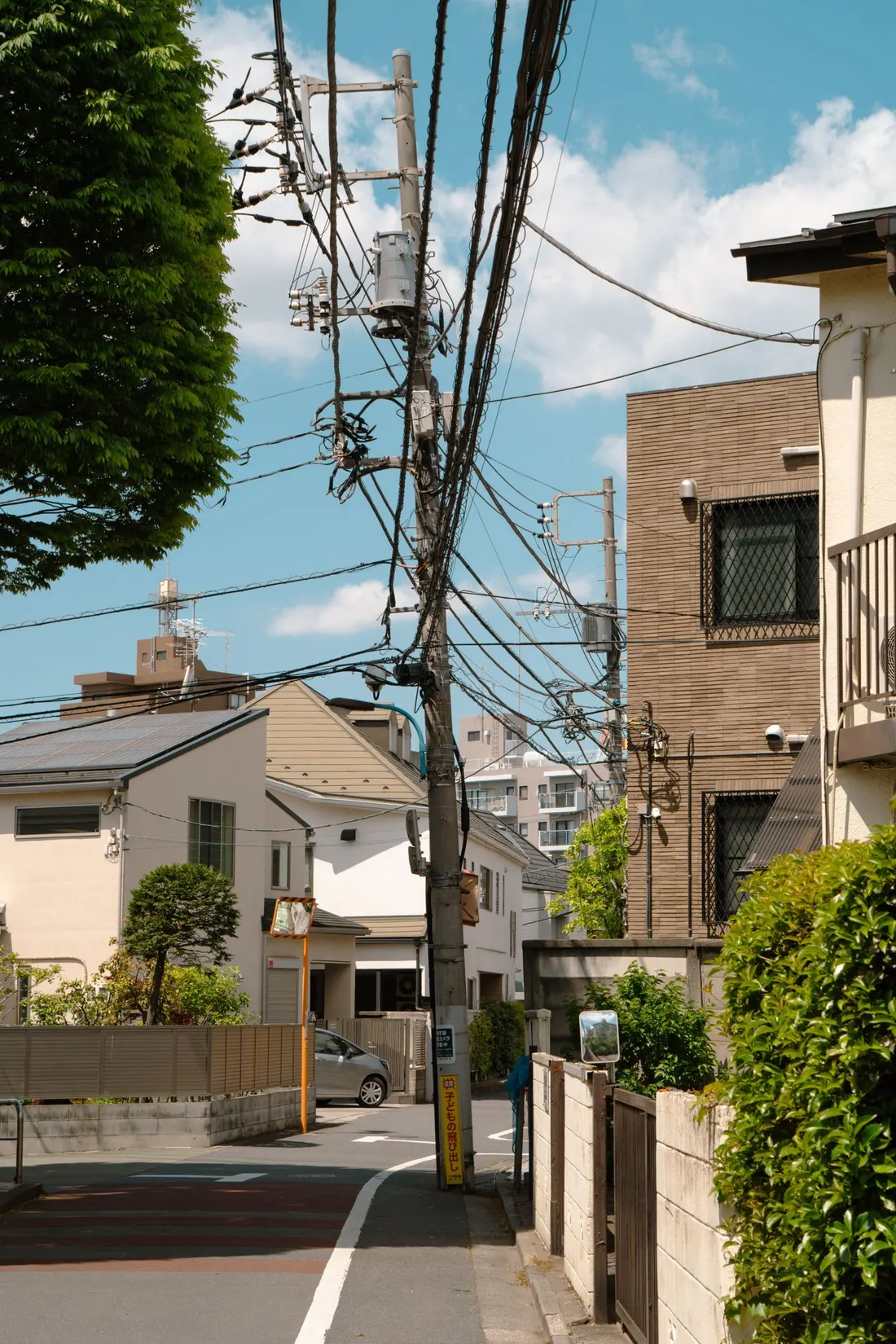 日本の住宅街の坂道。電柱と電線が並び、両側に住宅が建っている