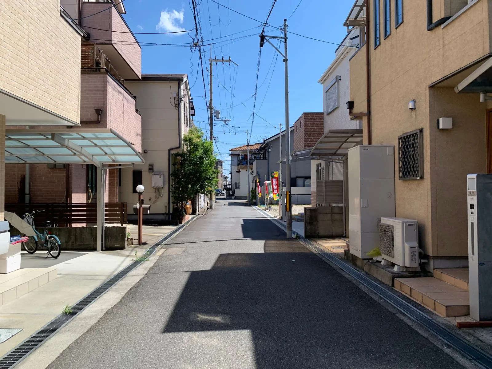 青空の下、電線が伸びる日本の住宅街の細い道路