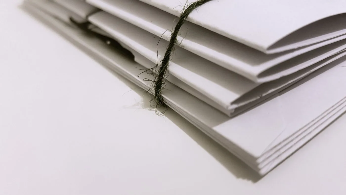 白い面の上に、細いひもで束ねられた書類が重ねて置かれている