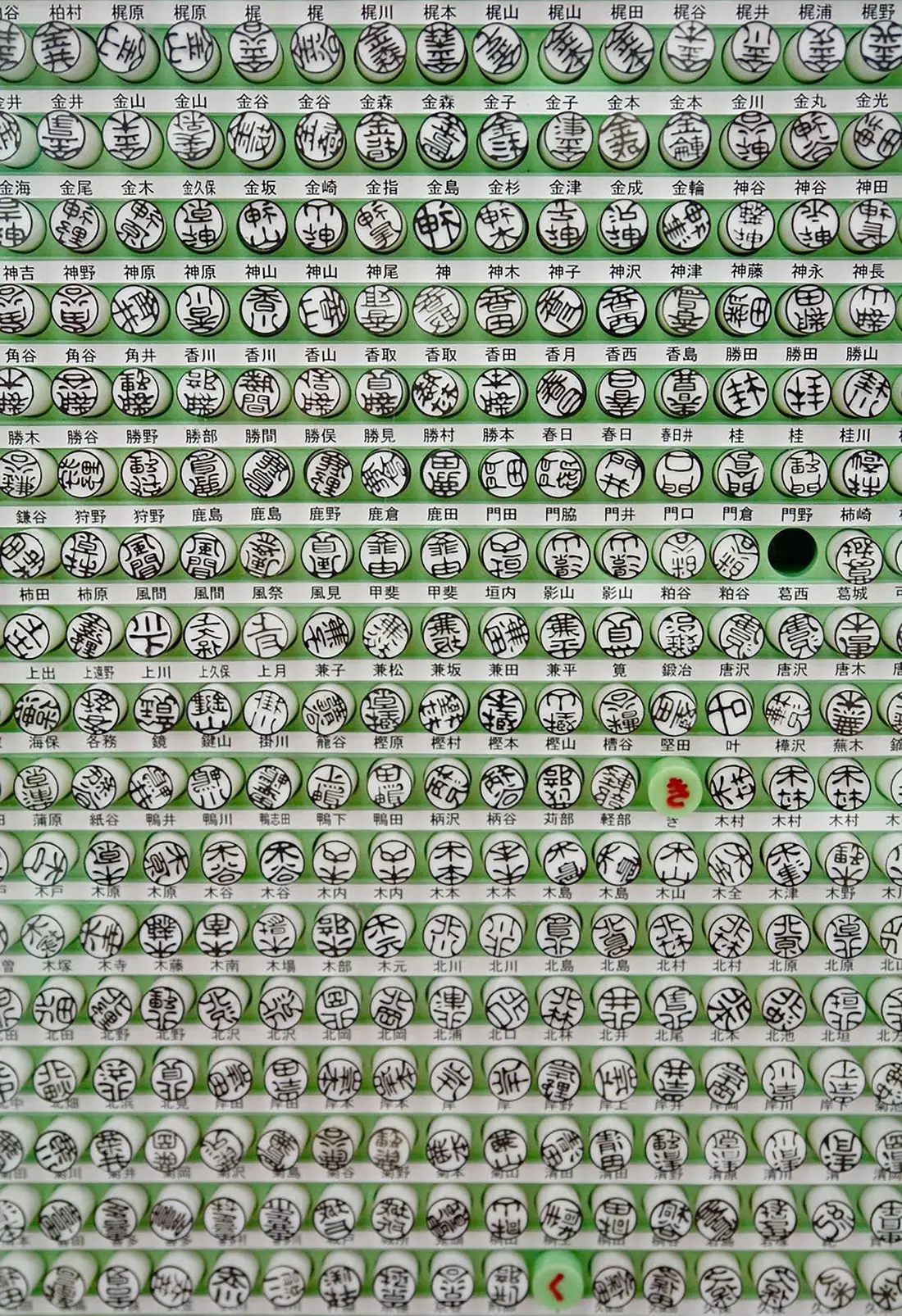 苗字の札とともに棚に並ぶ、丸い印面の既製の印鑑