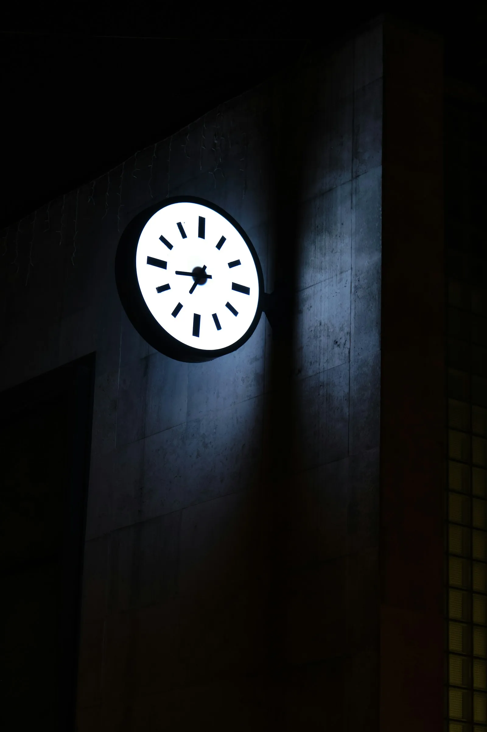 夜の建物の壁で明かりに照らされている丸い時計