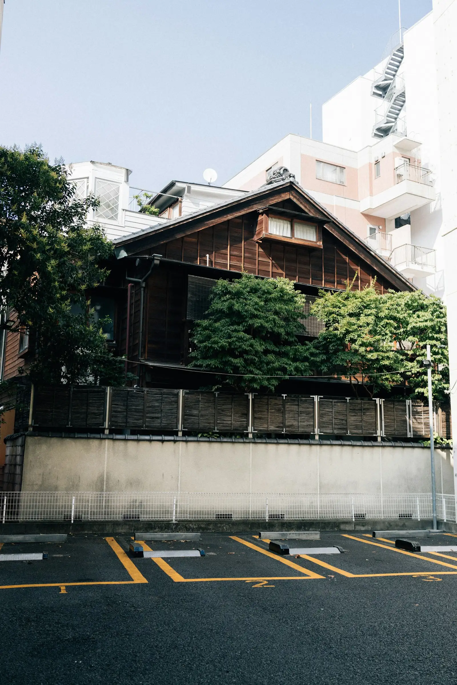 現代的なビルに囲まれて建つ古い木造の日本家屋