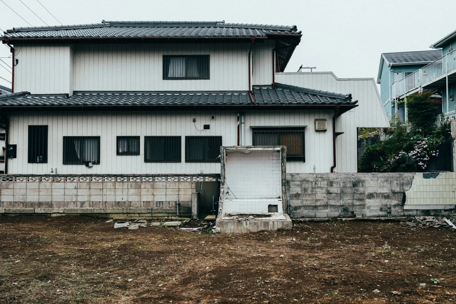 瓦屋根の日本家屋と、その前に広がる更地