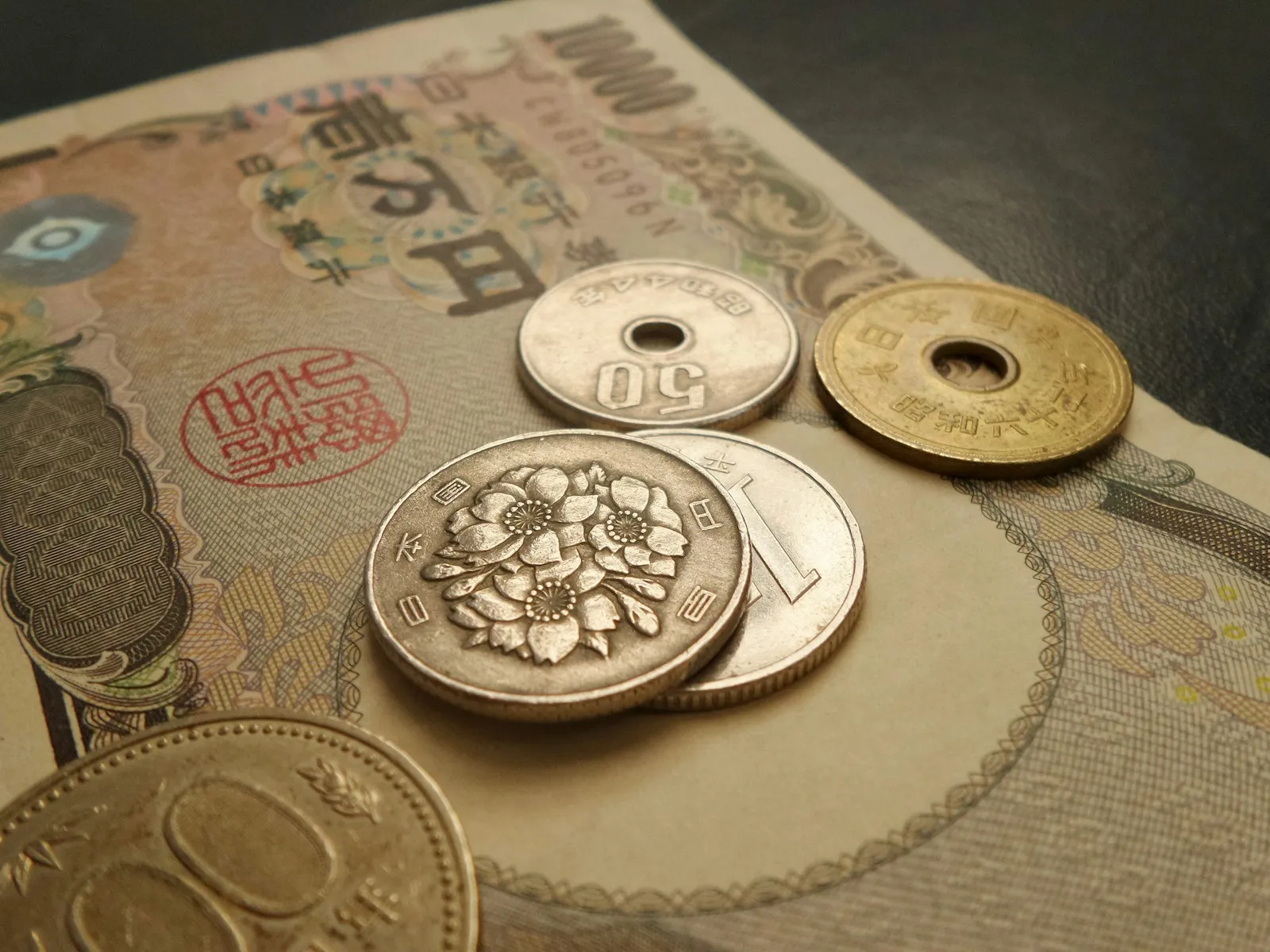 一万円札の上に重ねて置かれた1円玉・5円玉・50円玉